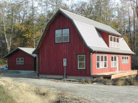 A red barn style house with a metal roof.