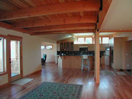 A kitchen with wood floors and wooden ceiling beams.