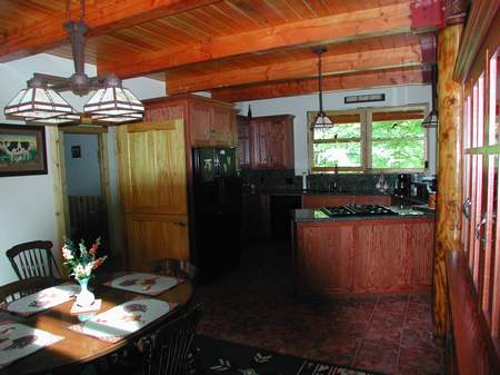 A kitchen with wood cabinets and wooden floors.