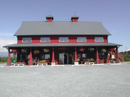 A red barn with many windows and tables in front of it.