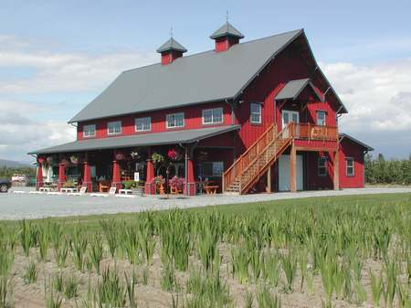 A red barn with grass growing in front of it.